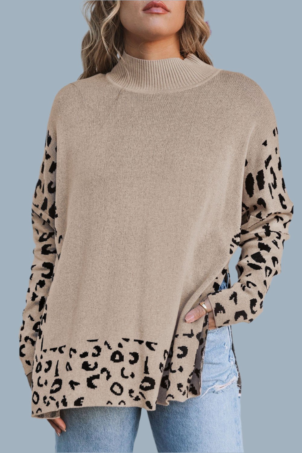 Beige sweater with leopard print sleeves worn by a person on a blue background