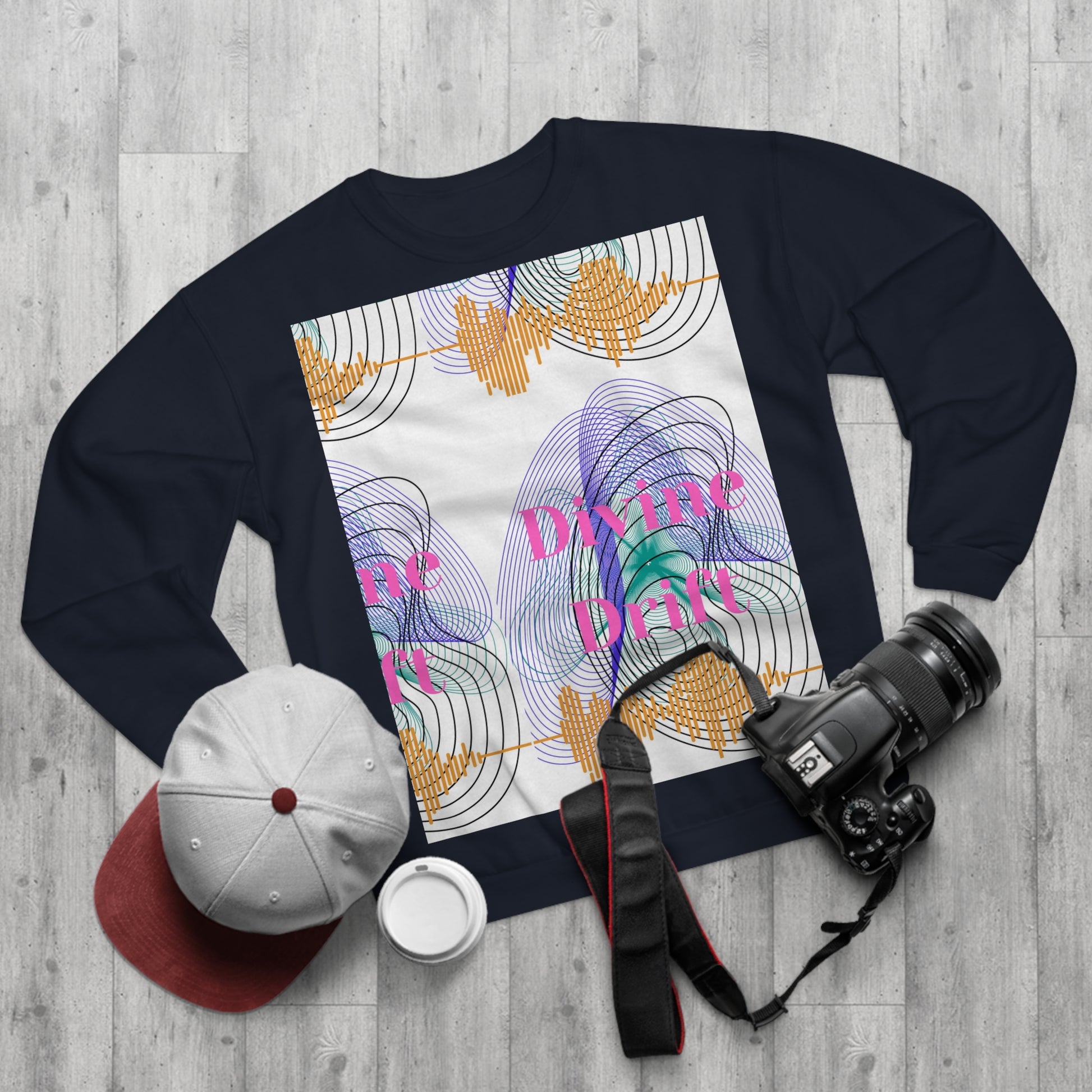 Black sweatshirt with abstract design and text on a wooden surface with accessories.